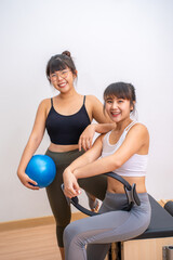 Fototapeta premium Two young happy Asian women posing and smiling for camera during their exercise break