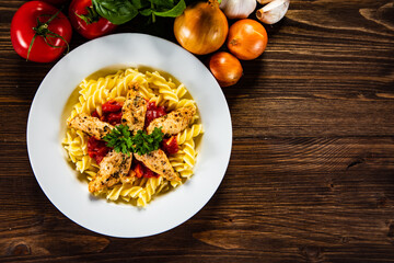 Chicken ragout with fusilli on wooden table
