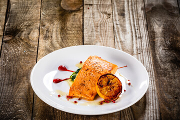 Fried salmon fillet with lemon served on wooden table 