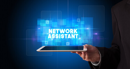 Young business person working on tablet and shows the inscription: NETWORK ASSISTANT