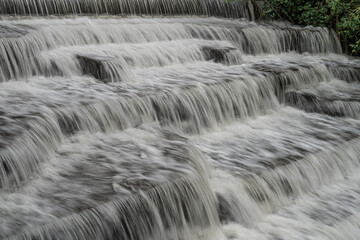 White Water flowing over weir low-level view at long exposure to give blurred motion effect