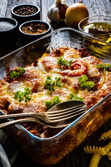 Pasta casserole with minced meat, mozzarella cheese and vegetables on wooden table
