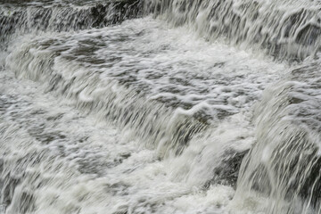 White Water flowing over weir low-level view at long exposure to give blurred motion effect