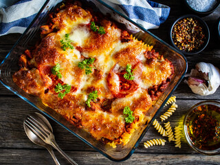 Pasta casserole with minced meat, mozzarella cheese and vegetables on wooden table
