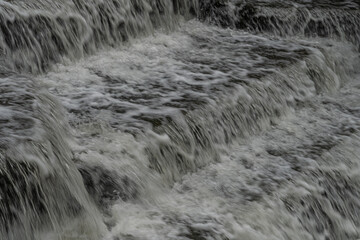 White Water flowing over weir low-level view at long exposure to give blurred motion effect