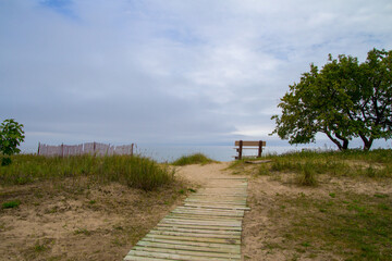 End Of The Journey. Boardwalk path ends at an empty park bench on a remote lonely beach. 