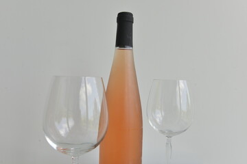 Wine bottle and empty glass isolated on a white wall