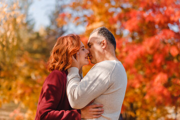 Fototapeta premium A middle-aged couple kisses in the park in the fall.