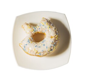 Close up view of bitten donut on white plate isolated on white background.  Food and health concept.