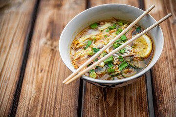 Spicy asian Korean kuksi soup in bowl on wooden table background