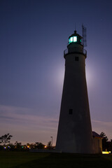 Illuminated Lighthouse Silhouette At Night. Illuminated beacon of the Fort Gratiot Lighthouse in Port Huron, Michigan. Vertical orientation and back lit by moonlight.