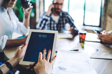 Faceless woman using tablet sitting together with colleagues