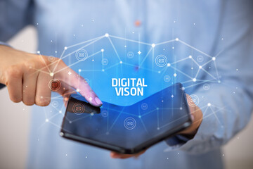 Businessman holding a foldable smartphone with DIGITAL VISON inscription, new technology concept