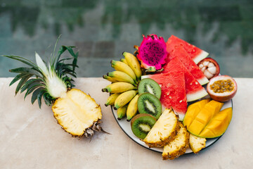 A plate of tropical fruits: watermelon, pineapple, bananas, mangosteen, passion fruit, mango and dragon fruit. Bali Indonesia. Summer time, relaxation travel concept