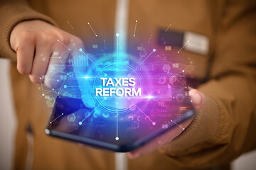 Businessman holding a foldable smartphone with TAXES REFORM inscription, new business concept