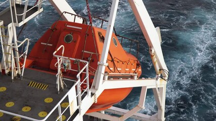 Orange freefall lifeboat on the stern of oil tanker.