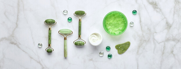 Cosmetic skin care products, jade stone face massager, creams, gel and oil. Roller massage of the face. Flat lay, top view © Irina Burakova