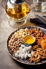 Assorted nuts and dried fruits in oriental style on a platter - dried apricots, cashews, pistachios, almonds, and walnuts