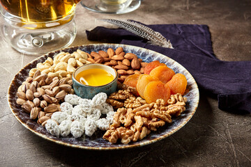 Assorted nuts and dried fruits in oriental style on a platter - dried apricots, cashews, pistachios, almonds, and walnuts