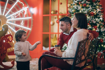Fototapeta na wymiar Family with a child near a New Year tree in Christmas decorations