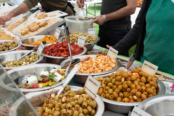 Mediterranean market stall. Pickled vegetables peppers, olives, garlic in large bowles on the counter