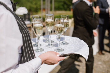 A waiter holding a tray with glasses with champagne at the party