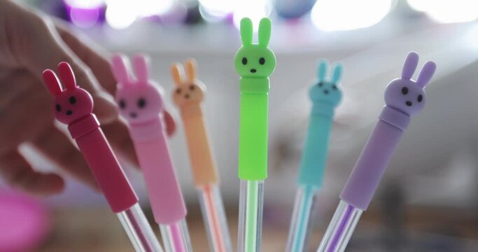 Bright colored pens with rabbits. Children's hand touches colored pens.