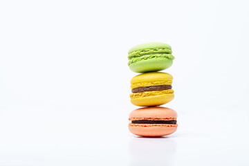 Macaroni, red, yellow and green, are stacked one on top of the other in the form of a tower on a white background. Side view