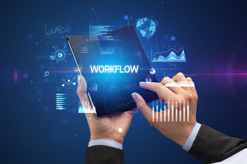 Businessman holding a foldable smartphone with WORKFLOW inscription, successful business concept