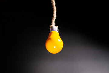 Concept idea. Yellow light bulb on black background.