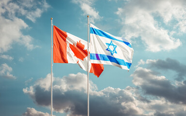 Canada and Israel flags waving at cloudy sky background. Concept of international Canadian Israeli relations.