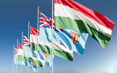 Hungary and Fiji flags waving at sky background. Concept of international Hungarian Fijian relations.
