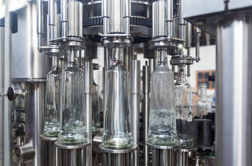 Pisco factory with machine blowing bottles and putting the caps on the bottles. Pisco bottling process.
