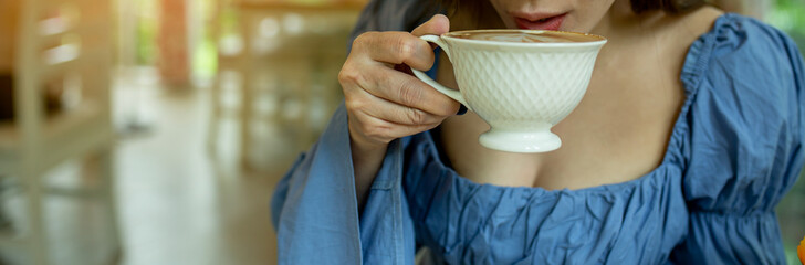 Close up of Asian female holding hand a cup of coffee in coffee shop.