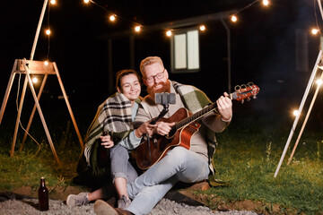 Young couple on a picnic with a guitar take a selfie or video communication with friends or relatives