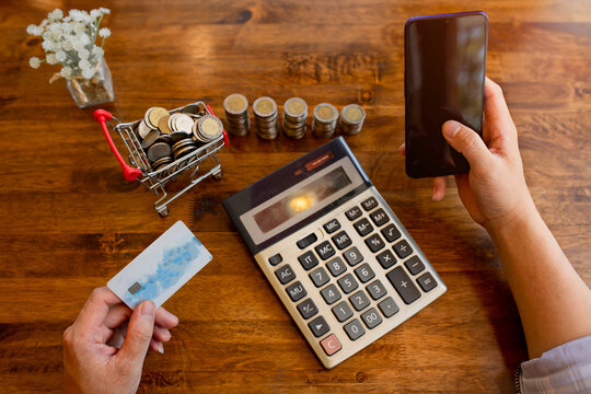 The holding hands smartphone and using credit card for online shopping on wooden table.Online payment,Top View.