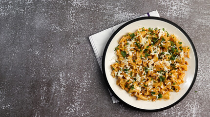 Pasta with cheese and meat with herbs on a round plate on a dark background. Top view, flat lay