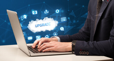 Businessman working on laptop with UPGRADE inscription, modern technology concept