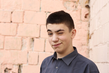 Fototapeta premium happy teenager boy wink closeup portrait on white wall background