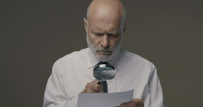 Businessman checking a document with a magnifier