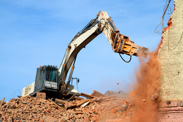 excavator demolishing a brick building. Machinery Demolishing Building