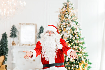 Happy Santa Claus indoors near christmas tree carrying no gifts to children