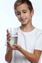 Cute boy with white background, wearing braces on his teeth. Spray a disinfectant mouthwash in the throat.