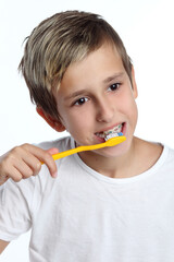 boy cleaning his teeth over white background