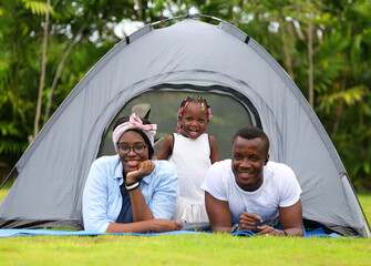 Happy African American family spending time together during vacation on the camping tent outdoor national park