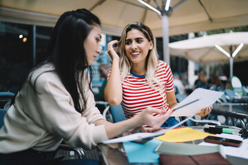 Fototapeta premium Young female students preparing to university exams analyzing course work report during cooperation, diverse women have brainstorming business meeting for collaborating on statistics paperwork