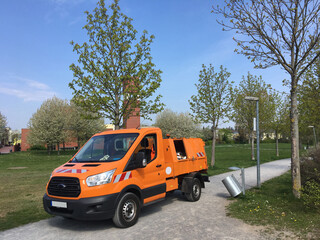 Fototapeta na wymiar Waste collection vehicle collecting litter bins in a park