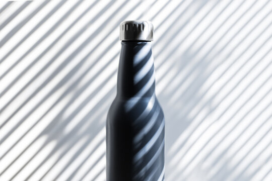 Close-up Of Steel, Eco Reusable Thermo Water Bottle On Background Of Shadows In Form Of Lines.