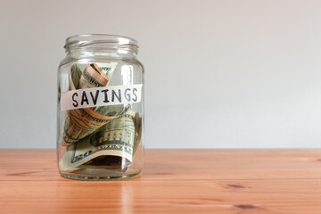 Money US Dollar bills in a glass jar labeled "savings". Saving financial concept