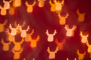 Defocused abstract bokeh lights christmas deer shape at red background. orange, gold and red colors. christmas and new year concept
